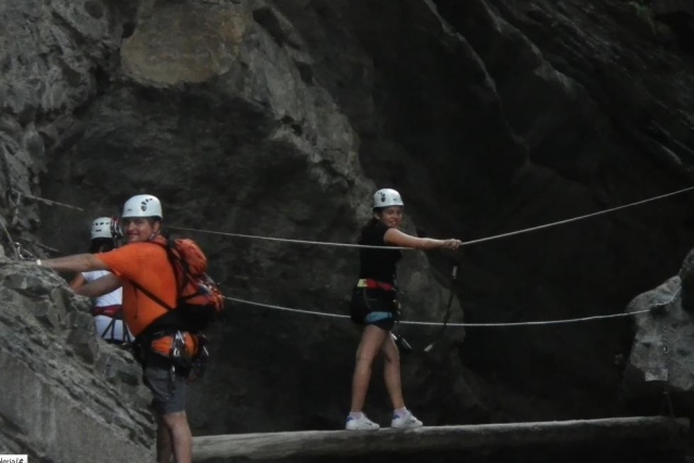  une fille passant devant une bûche étroite pendant que deux autres personnes attendent de la traverser 